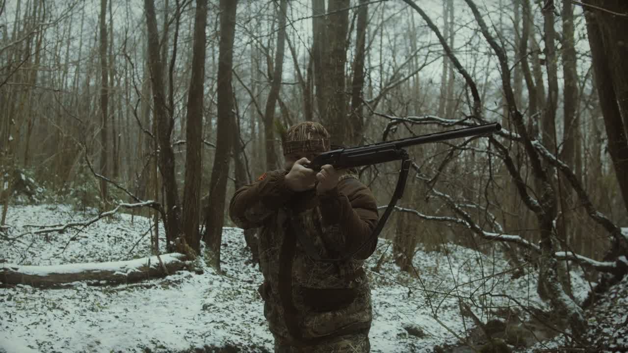 Hunter aiming rifle in winter forest
